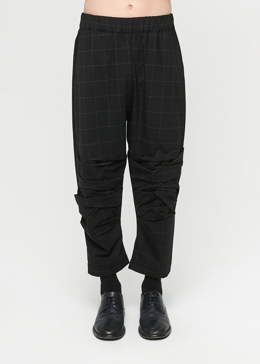 Black checkered pants worn by a person on a white background