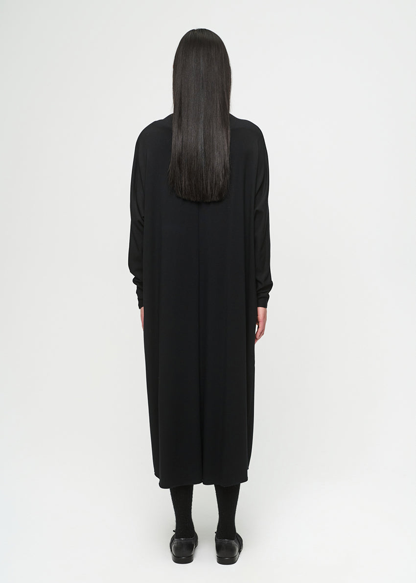 Person wearing a black, layered dress on a white background