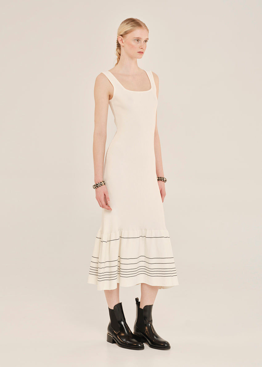 Woman wearing a white dress with black stripes on a plain background