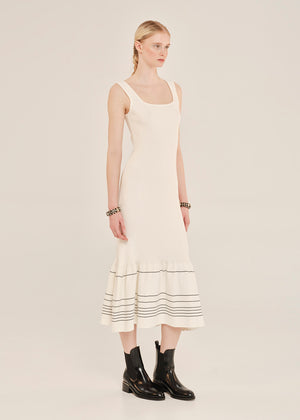 Woman wearing a white dress with black stripes on a plain background