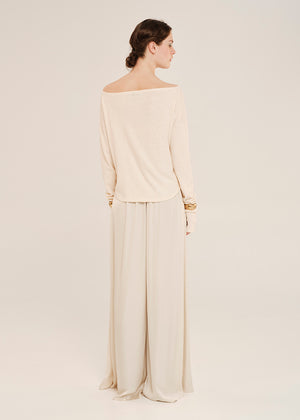 Woman wearing a beige off-shoulder top and wide-leg pants on a white background