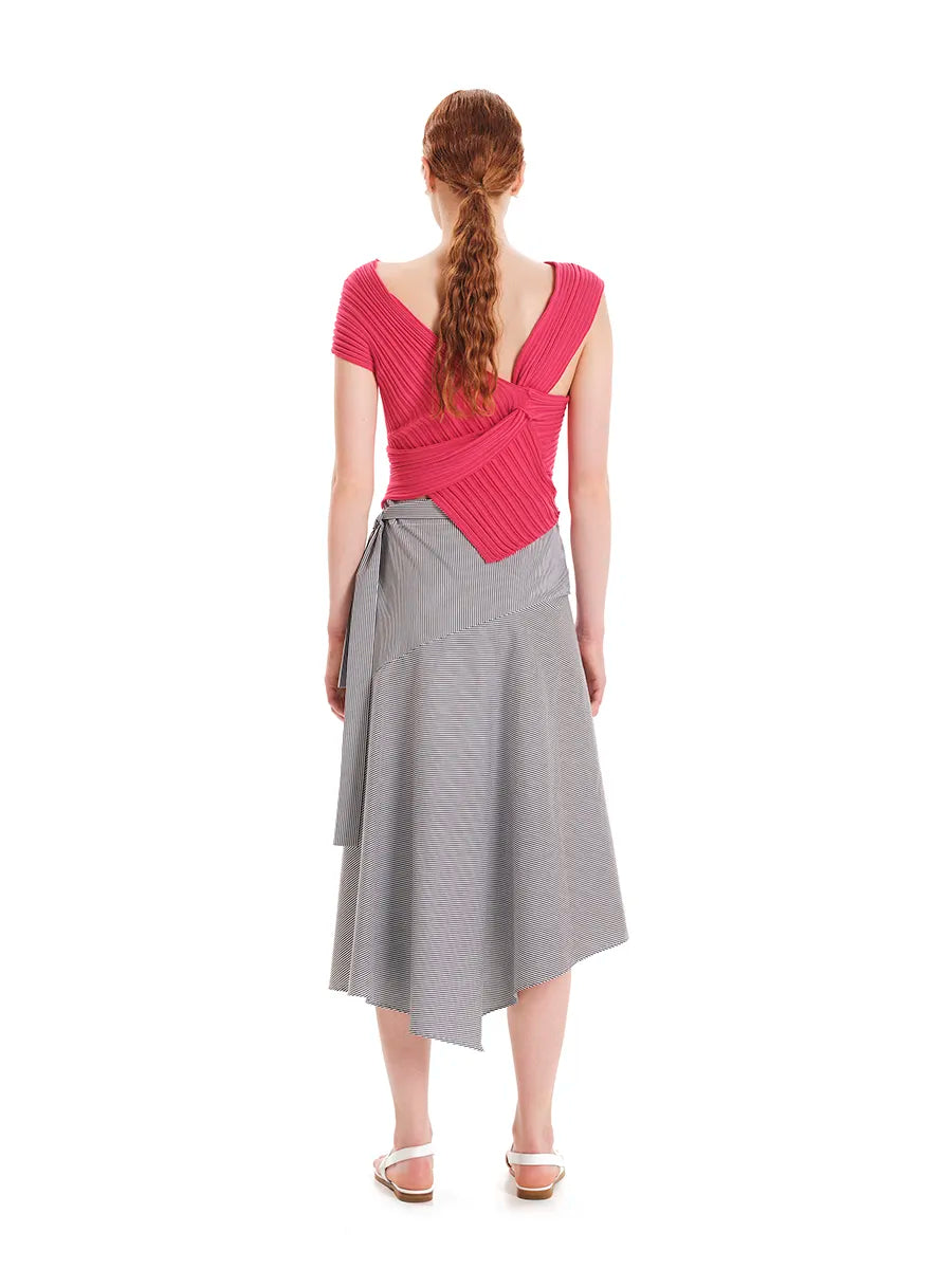 Woman wearing a pink top and gray skirt on a white background
