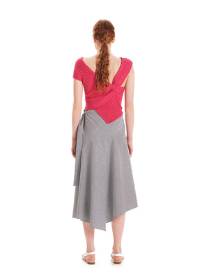 Woman wearing a pink top and gray skirt on a white background