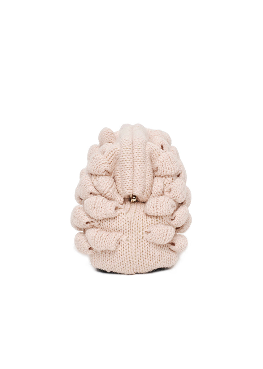 Cream-colored knitted clutch held by a person wearing a white sweater.