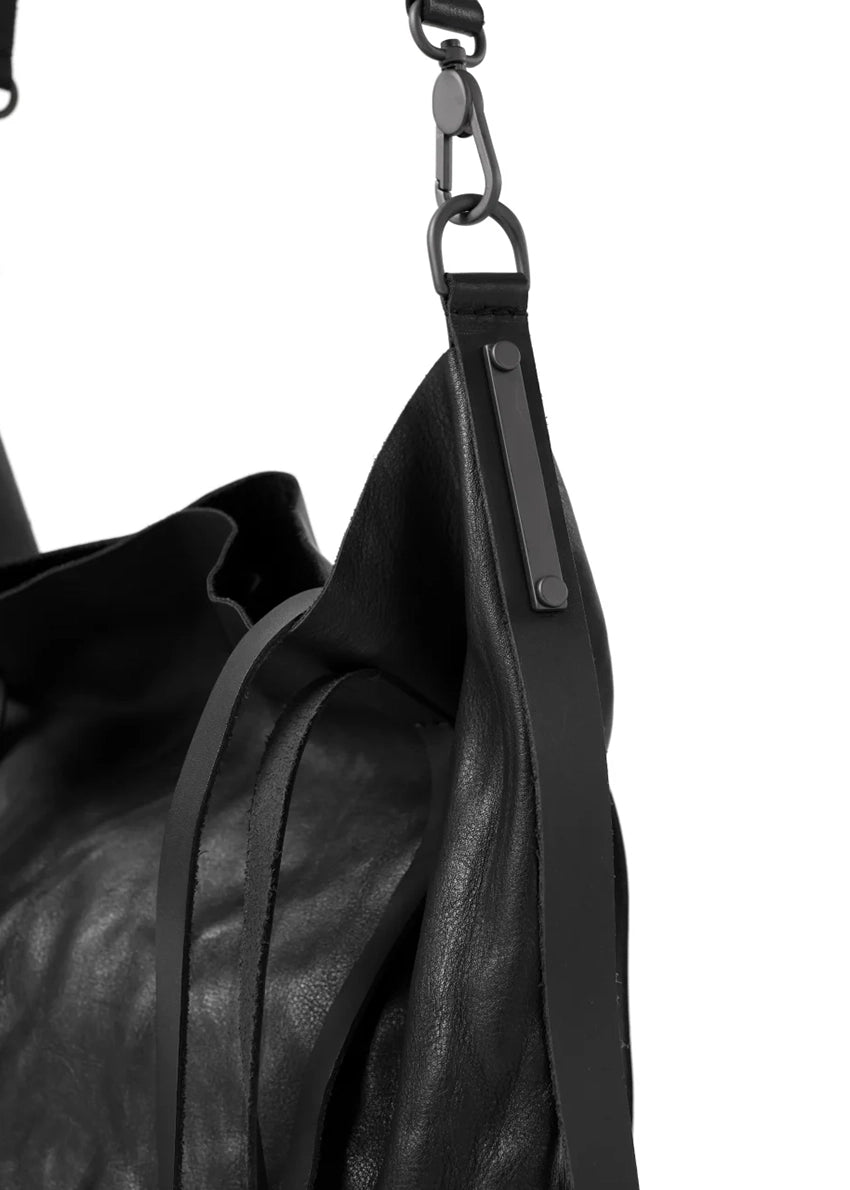 Close-up of a black leather bag with a strap on a white background