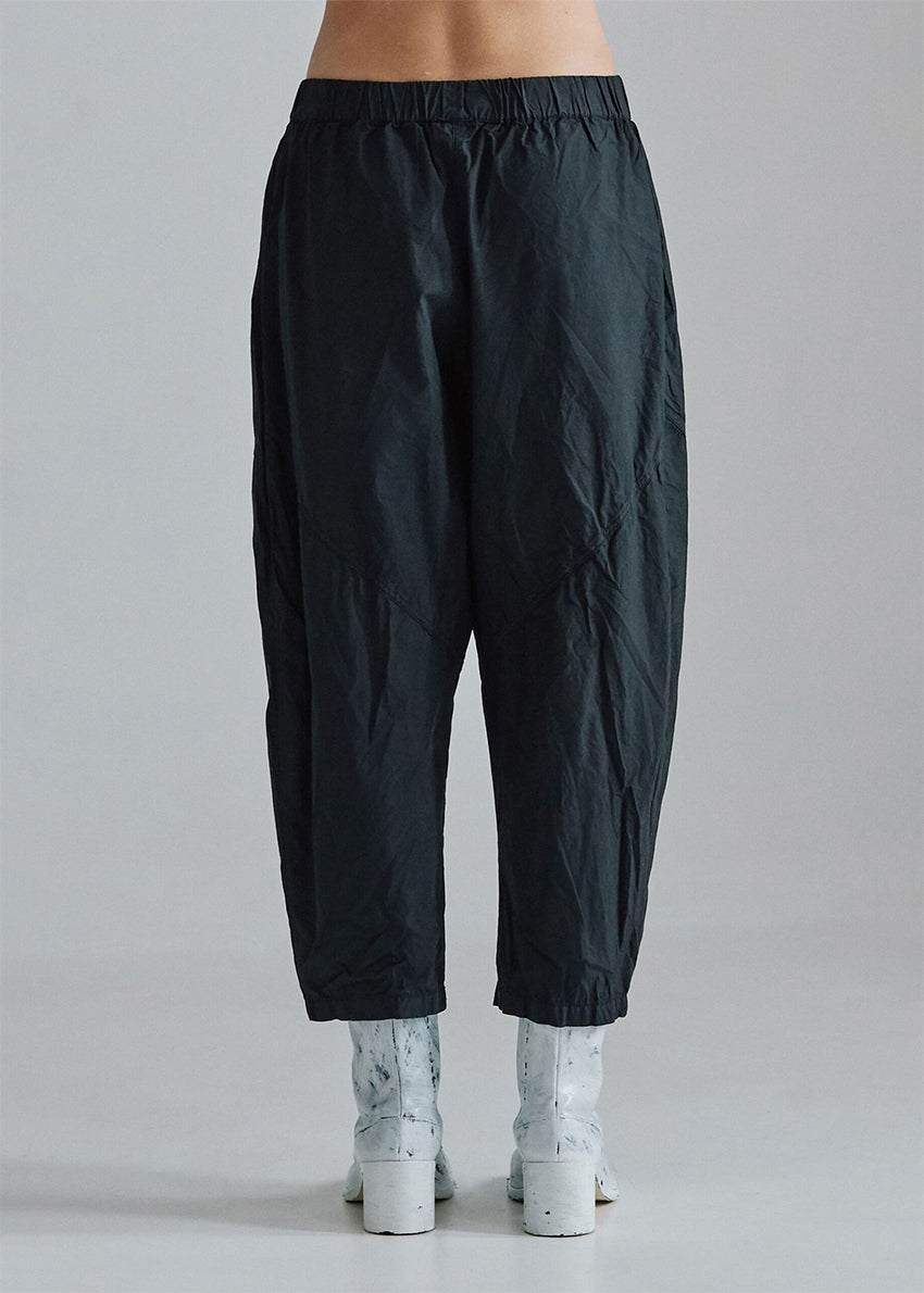 Cropped, drop-crotch unisex trousers, made from cotton poplin, in relaxed cut. These pants have an elastic waistband and diagonal seams just above the knee.