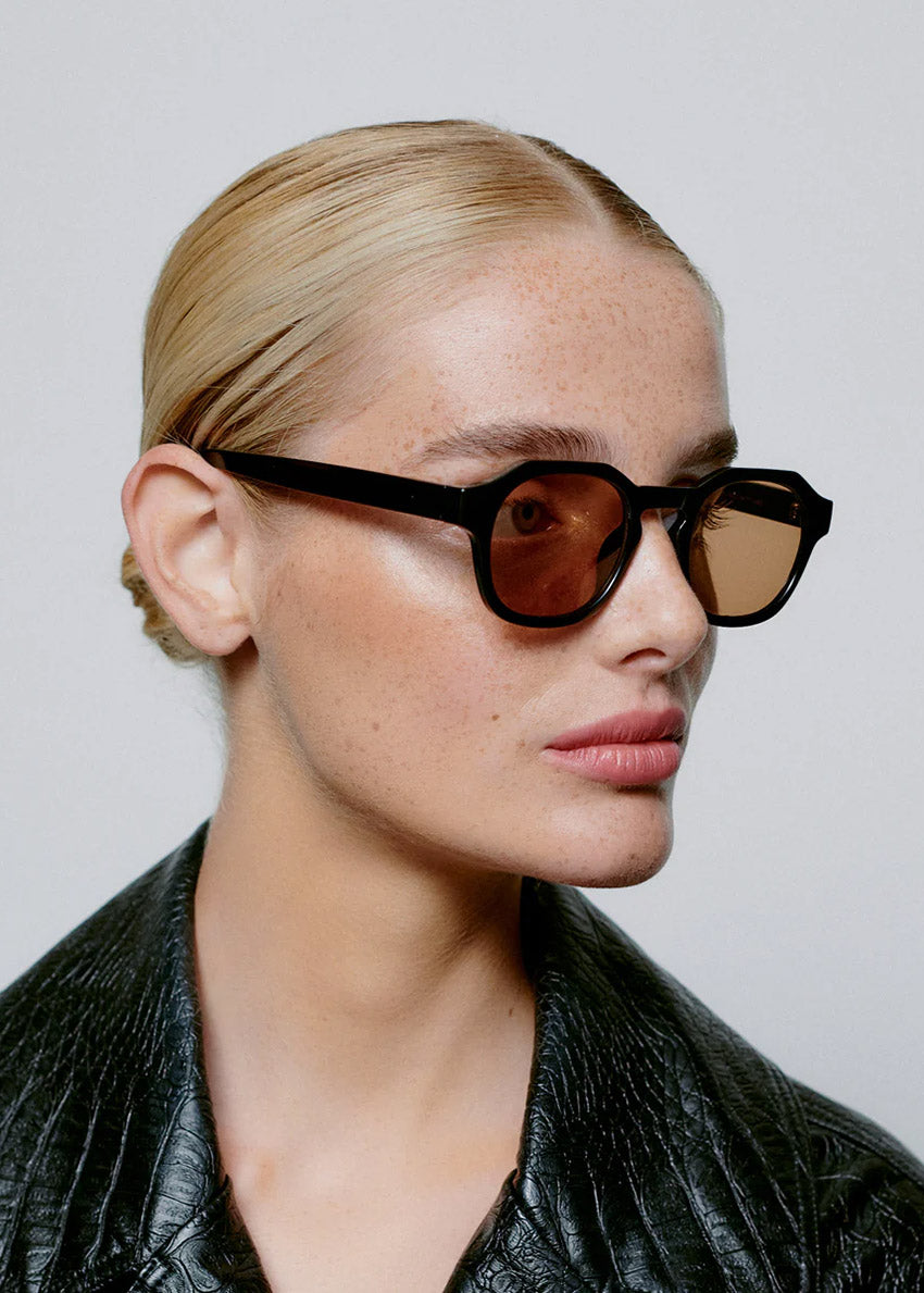 Person wearing sunglasses and a black leather jacket against a plain background