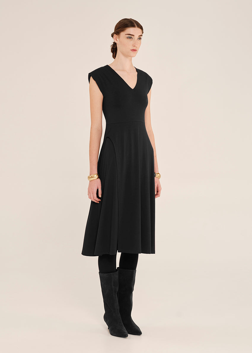 Woman wearing a black sleeveless dress with a plain background