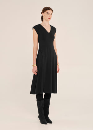 Woman wearing a black sleeveless dress with a plain background