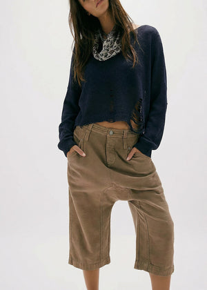 Person wearing a navy sweater and brown pants on a white background