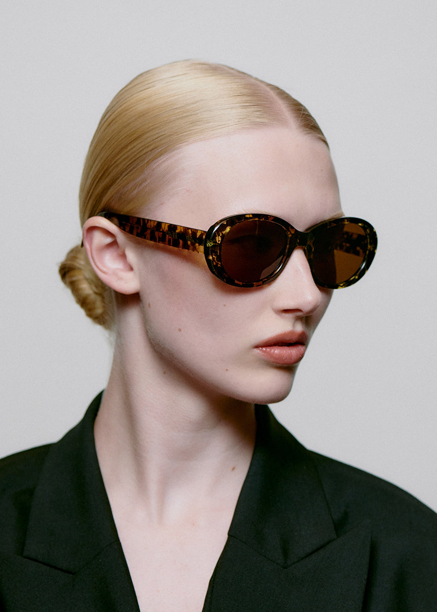 Model wearing leopard print sunglasses with a plain background
