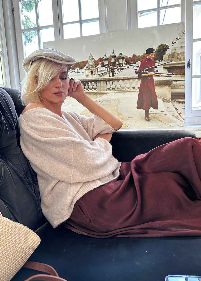 Woman sitting on a couch with a scenic painting in the background