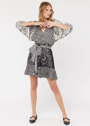 A woman modeling a black and white geometric patterned dress with bell sleeves and a belt.