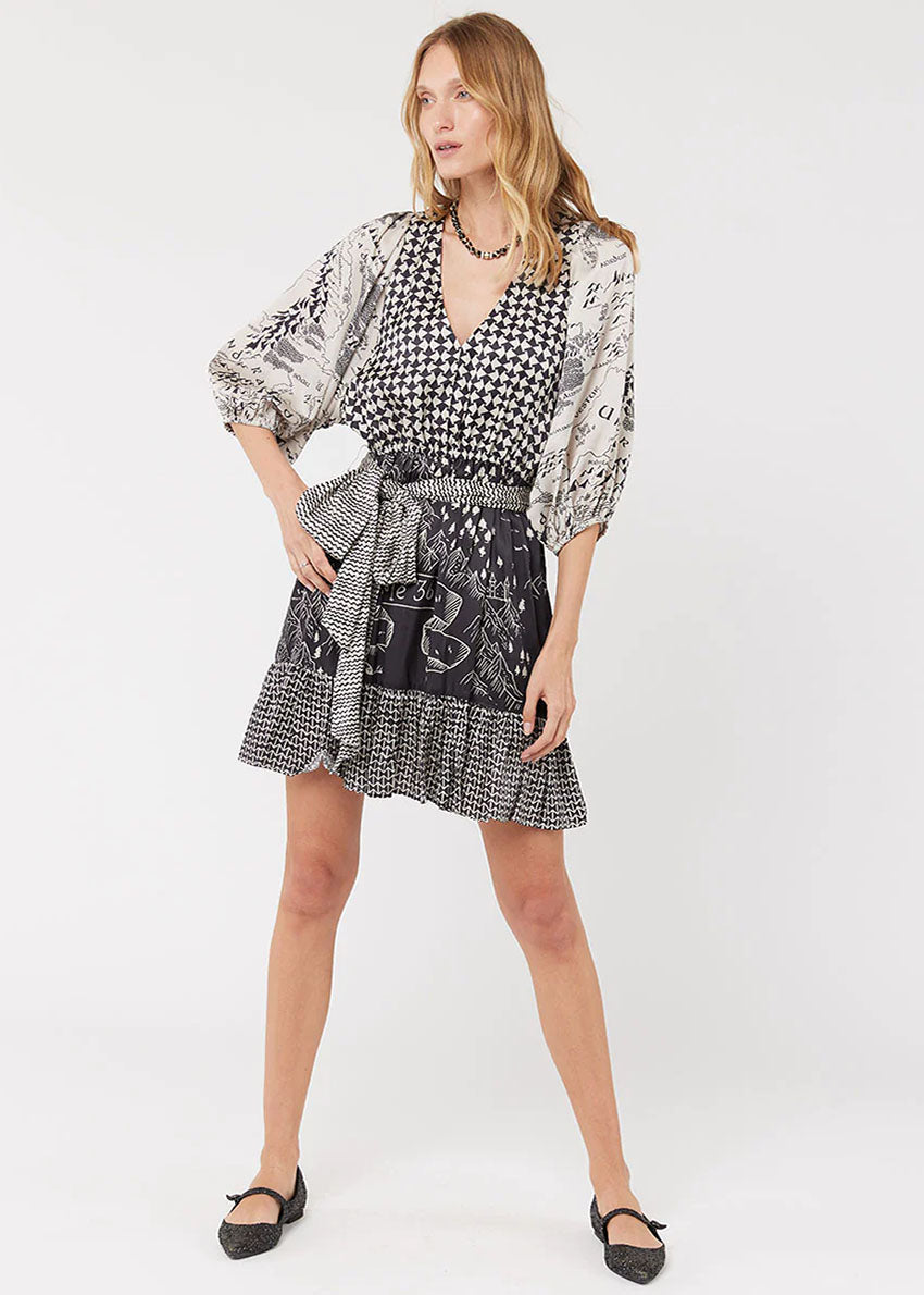 A woman modeling a black and white geometric patterned dress with bell sleeves and a belt.