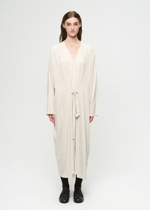 Person wearing a long, light-colored dress against a white background