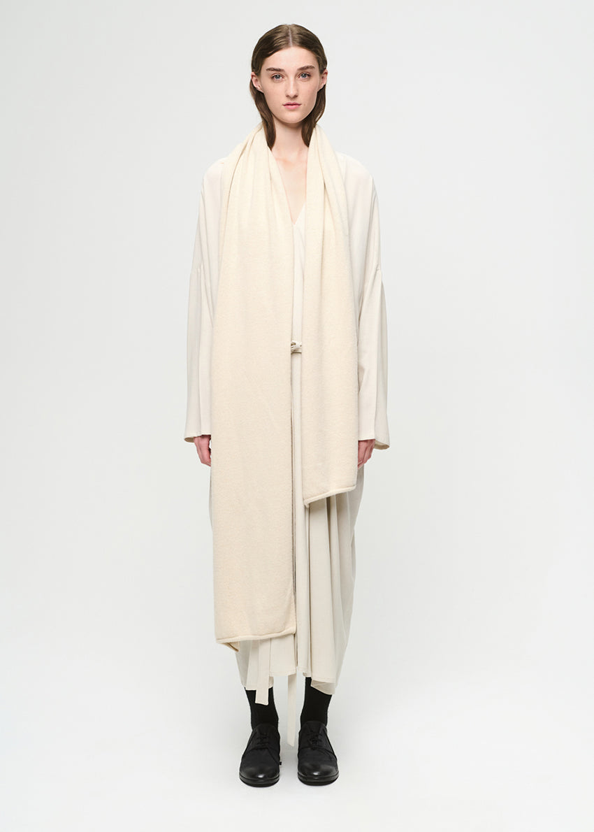 Person wearing a long beige scarf and dress on a white background