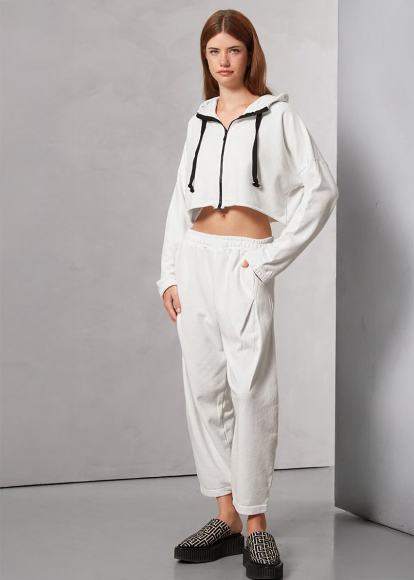 Woman wearing a white tracksuit with black accents against a gray background