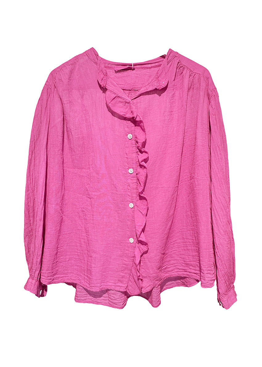 White blouse with ruffled details worn by a person against a neutral background