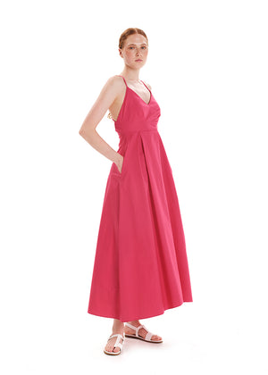 A model wearing a backless, asymmetric pink dress with a 'V' neck, side pockets, and an asymmetrical hemline.