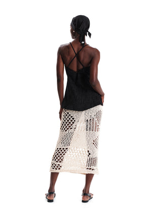 Woman wearing a black top and white patterned skirt on a white background