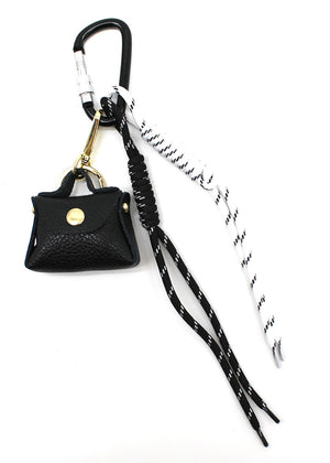 A multicolored braided rope keychain charm with heart shapes attached to a bag's zipper, displayed in a close-up image with a handbag in the background.