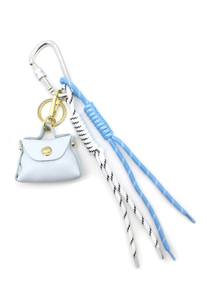 A multicolored braided rope keychain charm with heart shapes attached to a bag's zipper, displayed in a close-up image with a handbag in the background.