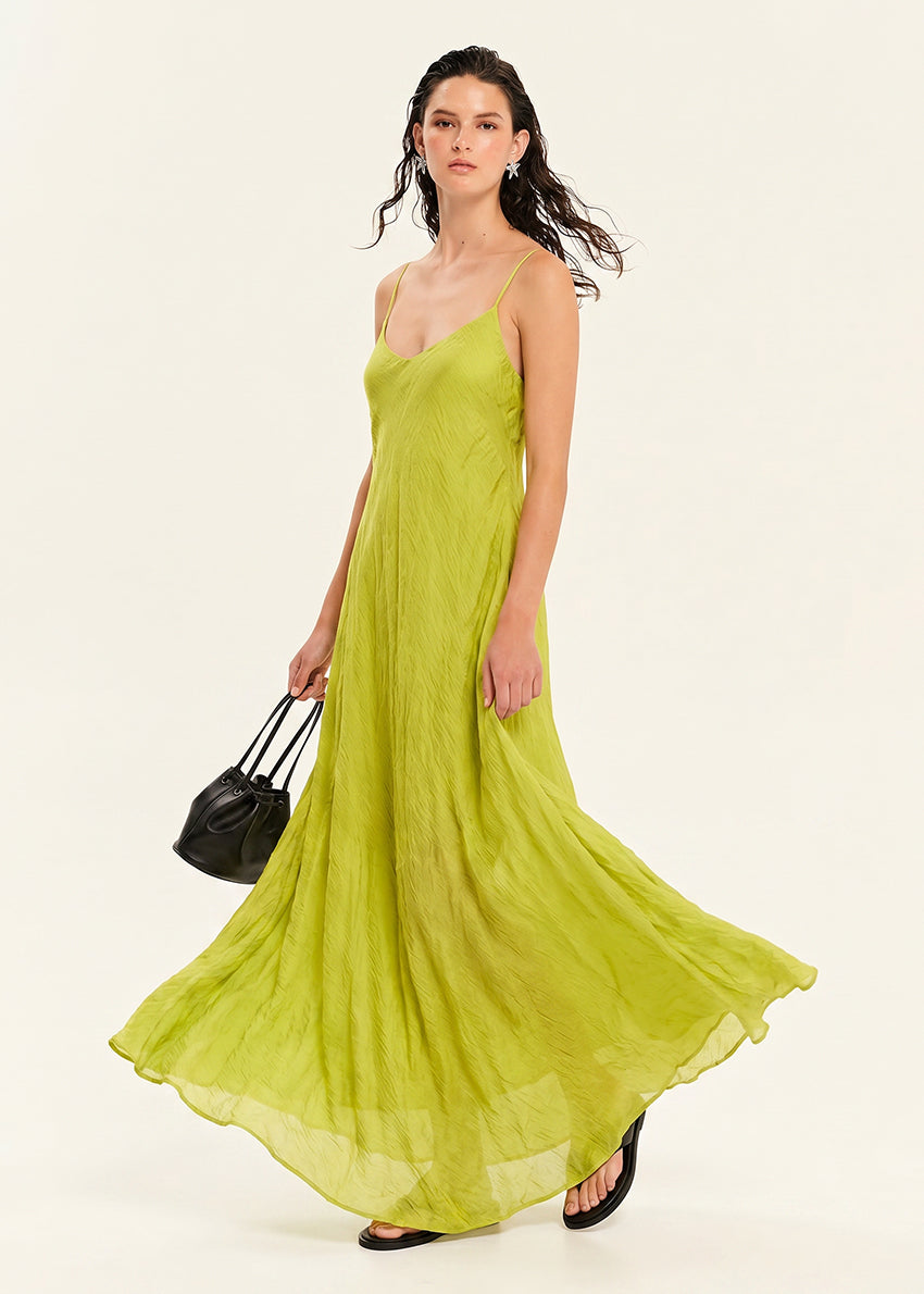 Woman wearing a white slip dress holding a black handbag on a beige background
