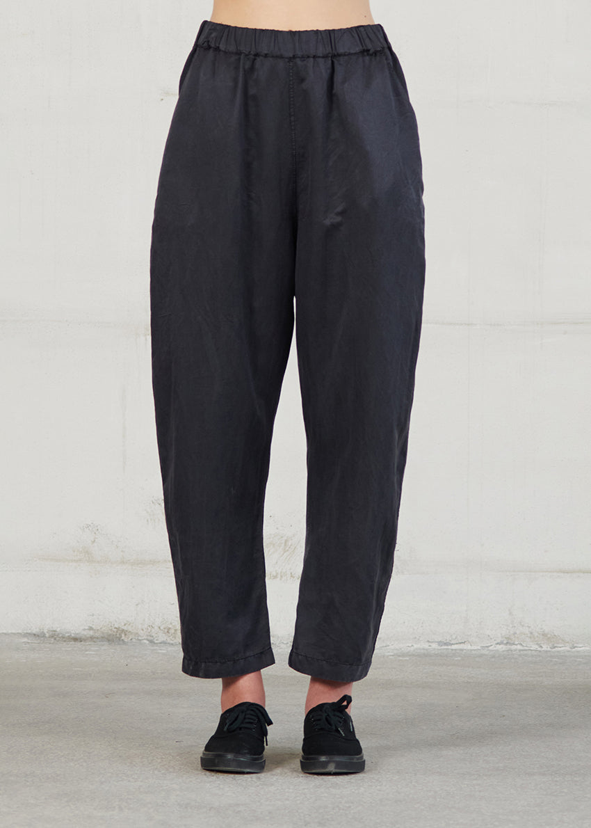 Person wearing black pants against a plain background