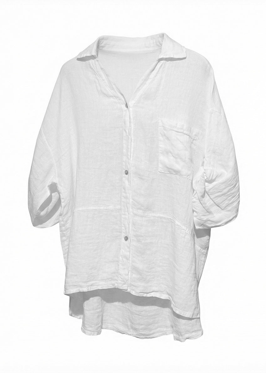 Woman wearing a white shirt and brown hat against a rustic wall.