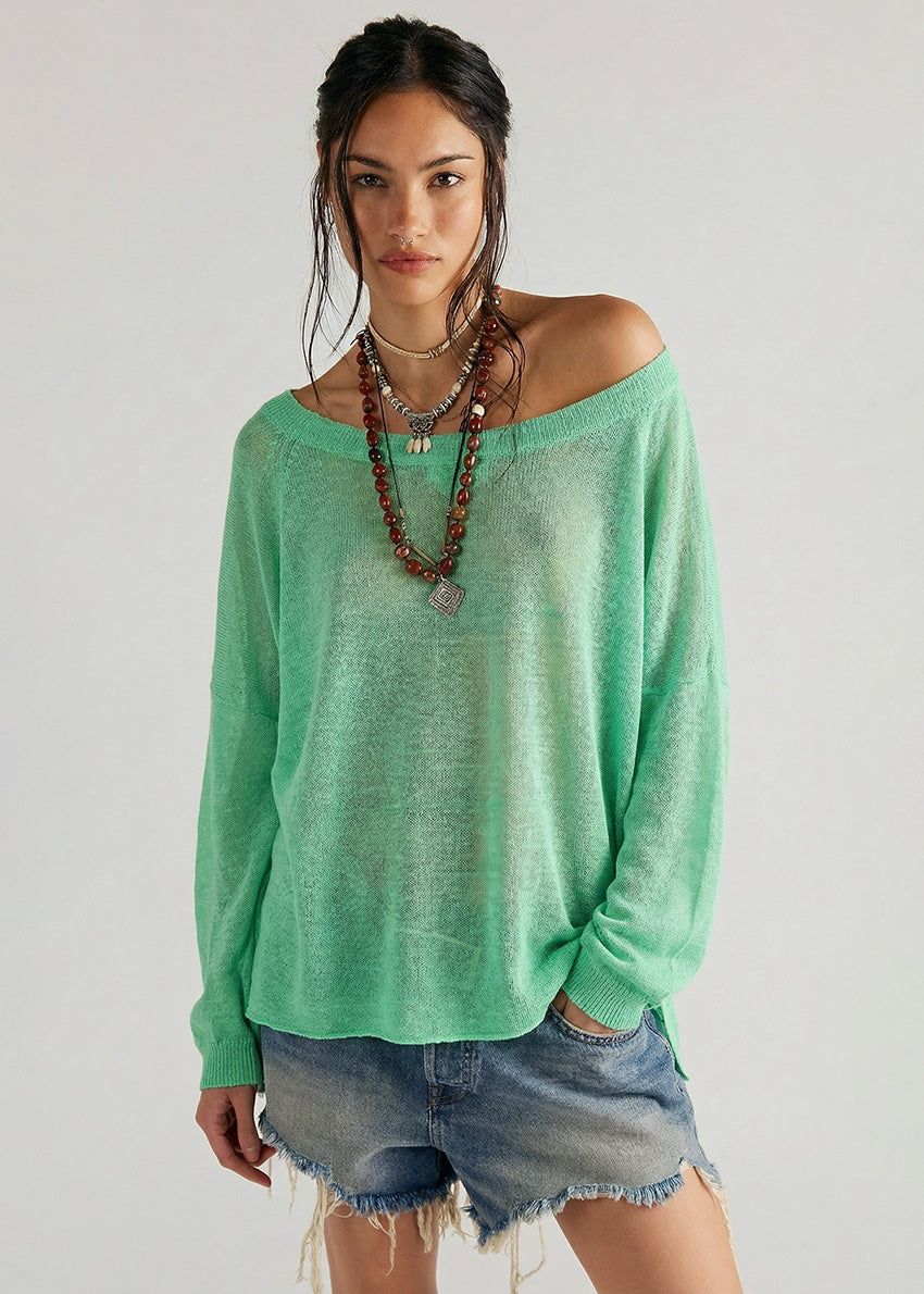 Woman wearing a green sweater and denim shorts against a plain background