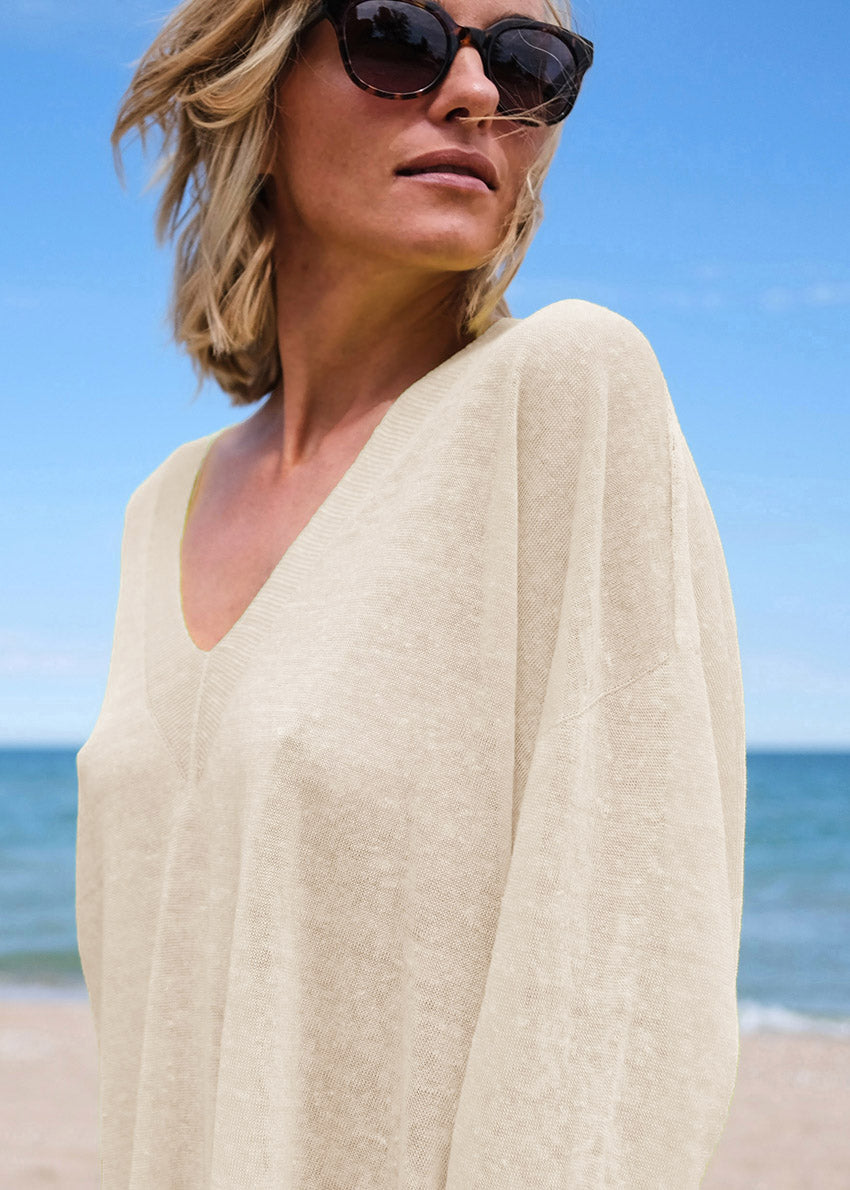 Woman in a beige cover-up on a beach with sunglasses