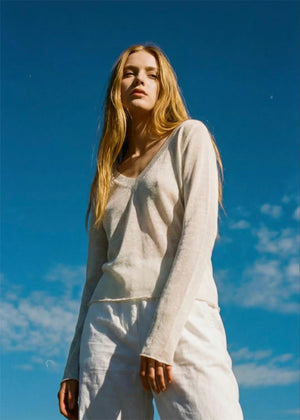 Woman in a light outfit standing against a blue sky