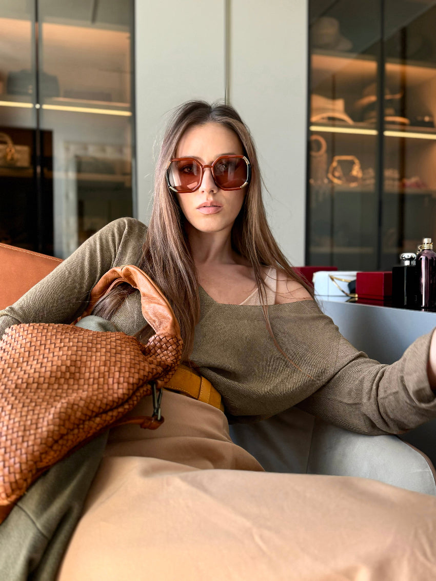 The sweater showcases a deep V-neckline at the front and back, adding a touch of sophistication to its minimalistic design.