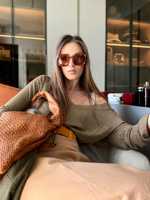 The sweater showcases a deep V-neckline at the front and back, adding a touch of sophistication to its minimalistic design.