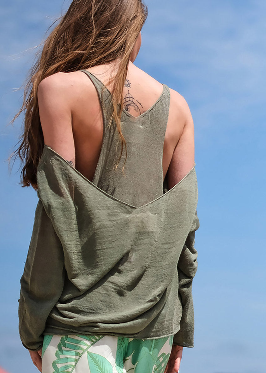 A back view of a person wearing a khaki green sleeveless top with a wide V-neckline and an open halter back.