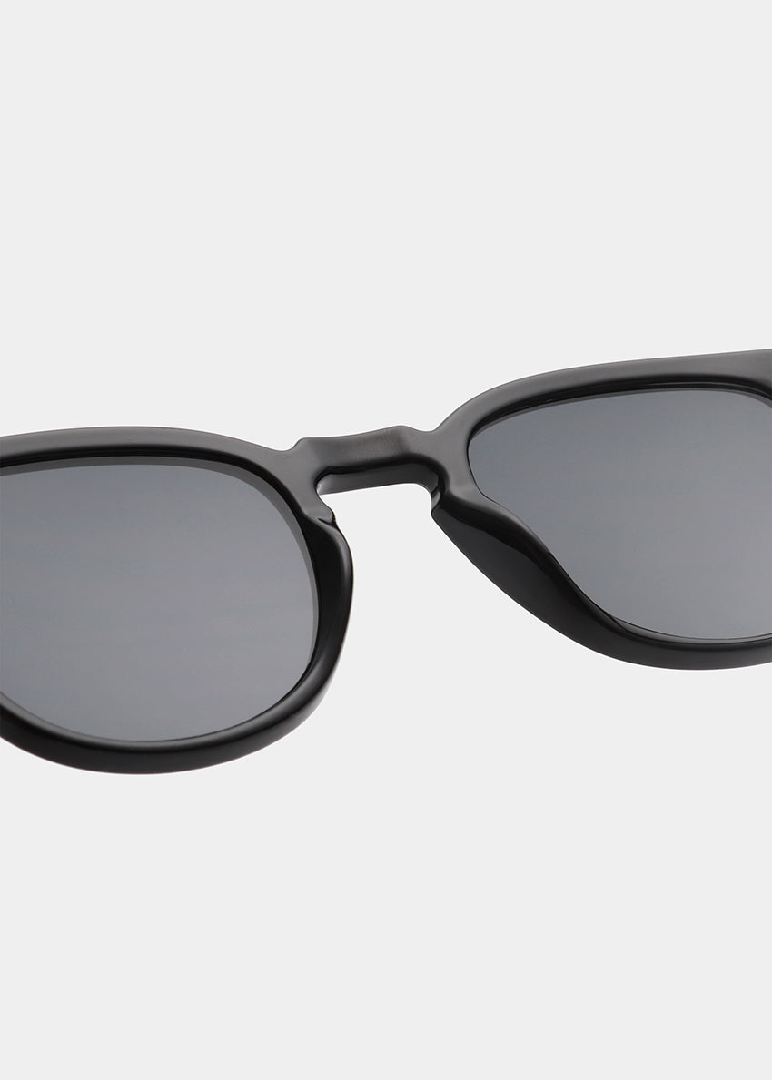 Black sunglasses with dark lenses on a light gray background