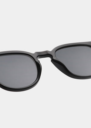 Black sunglasses with dark lenses on a light gray background