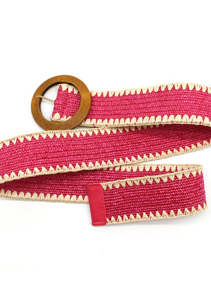 A pink raffia belt with a wooden buckle and decorative edge, against a white background.
