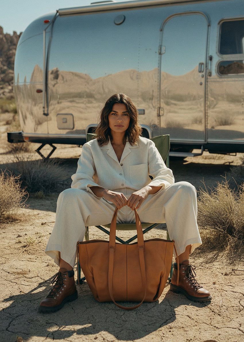 Woman sitting in front of a vintage trailer in a desert setting