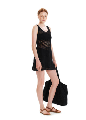 A sleeveless, black, knee-length dress with a straight neckline and intricate knit pattern, displayed on a white background with a necklace.