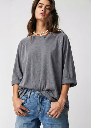 Woman wearing a gray oversized shirt and blue jeans on a white background