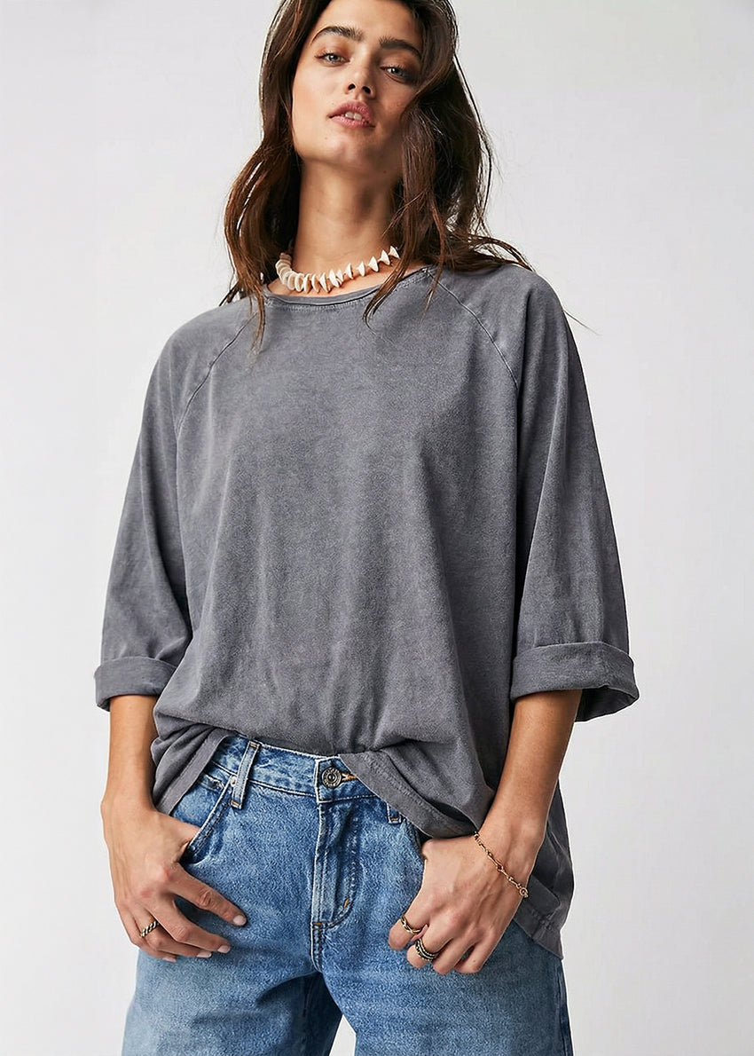 Woman wearing a gray oversized shirt and blue jeans on a white background