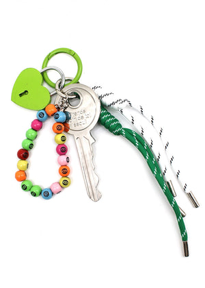 Keychain with colorful beads, green heart charm, and straw on a white background