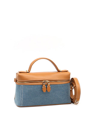 Blue denim handbag with brown leather accents on a white background