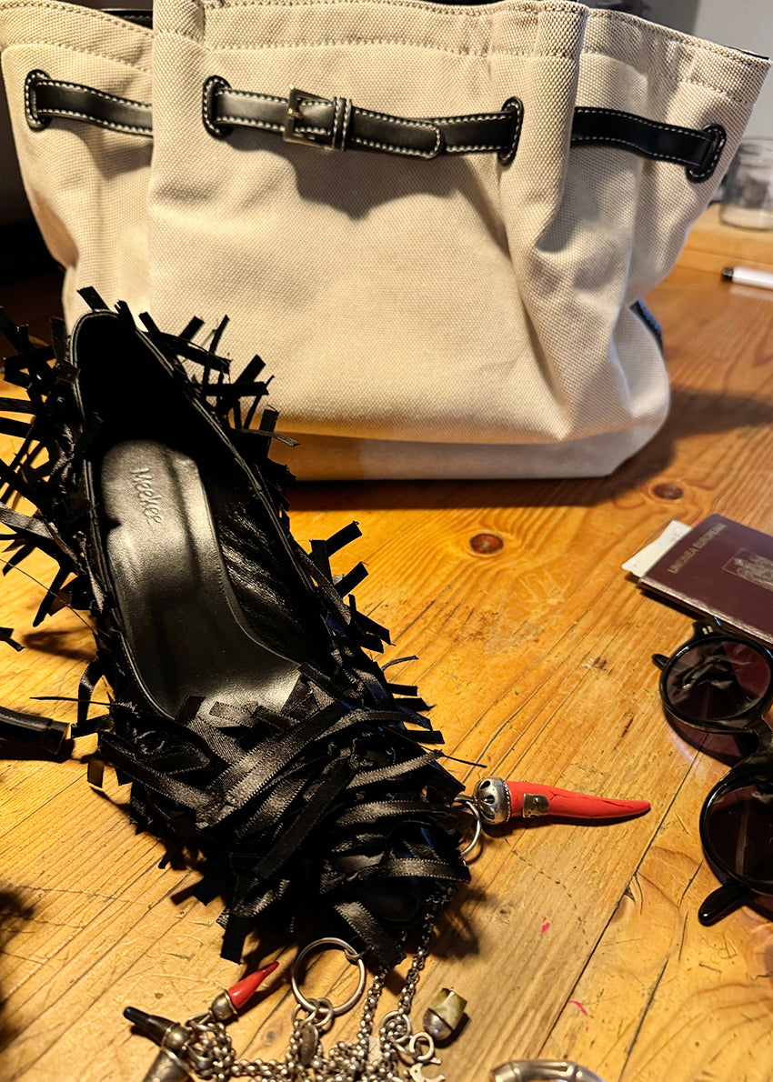 Light beige canvas tote bag with black leather handles and buckle accents. A spacious and durable design perfect for daily use