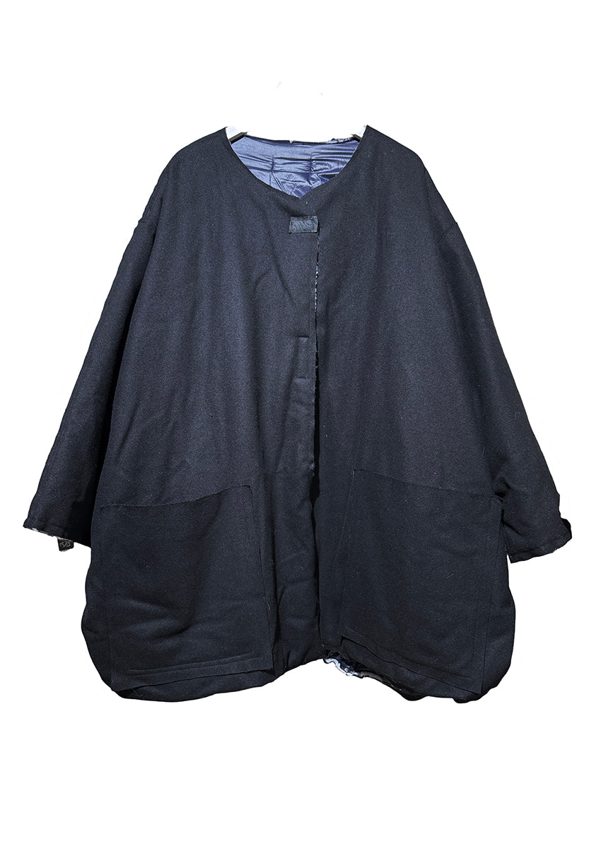 A double-faced jacket with a black front and blue fleece side, featuring pockets and a front closure with adhesive tape.
