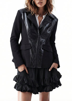 Person wearing a black leather jacket over a black ruffled dress on a white background