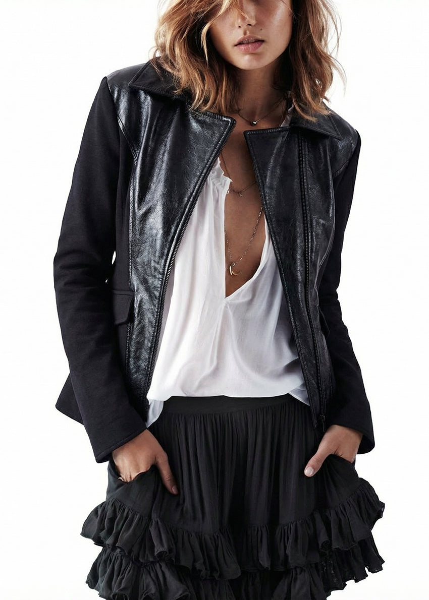 Person wearing a black leather jacket over a white top and black ruffled skirt on a white background