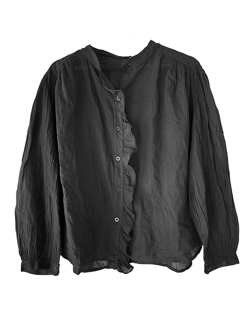 White blouse with ruffled details worn by a person against a neutral background