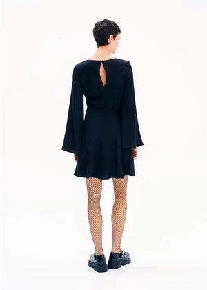 A model wearing a black mini dress with long bell sleeves and a V-neckline, standing against a white background.